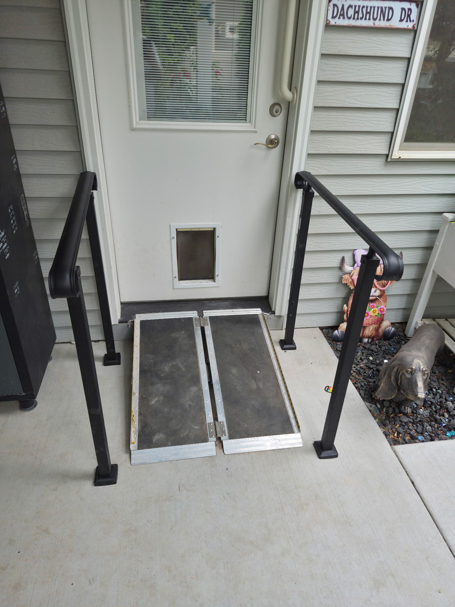 Wheelchair ramp and black handrails installed at residential entry