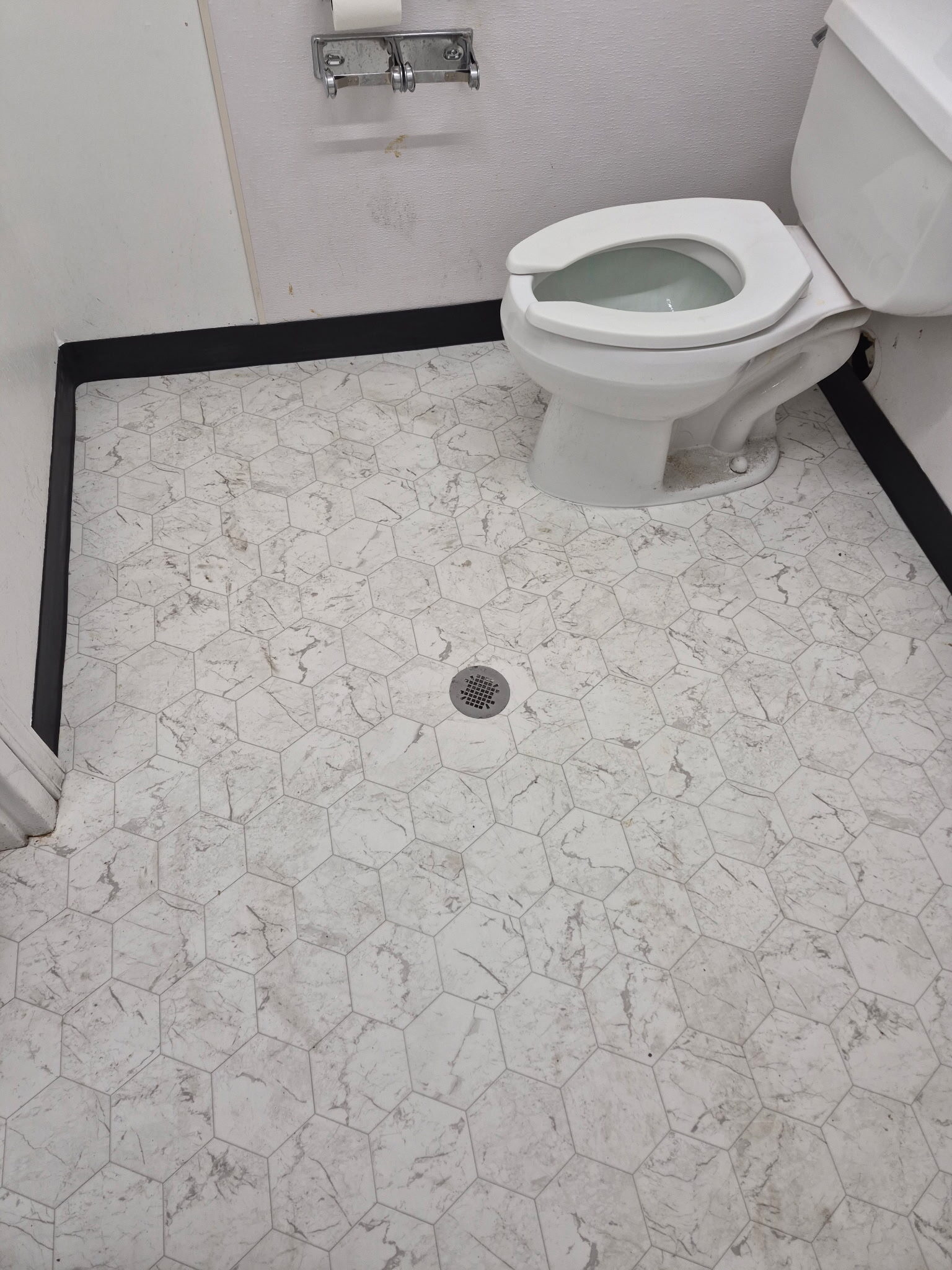 White marble hexagon tile floor with center drain in bathroom