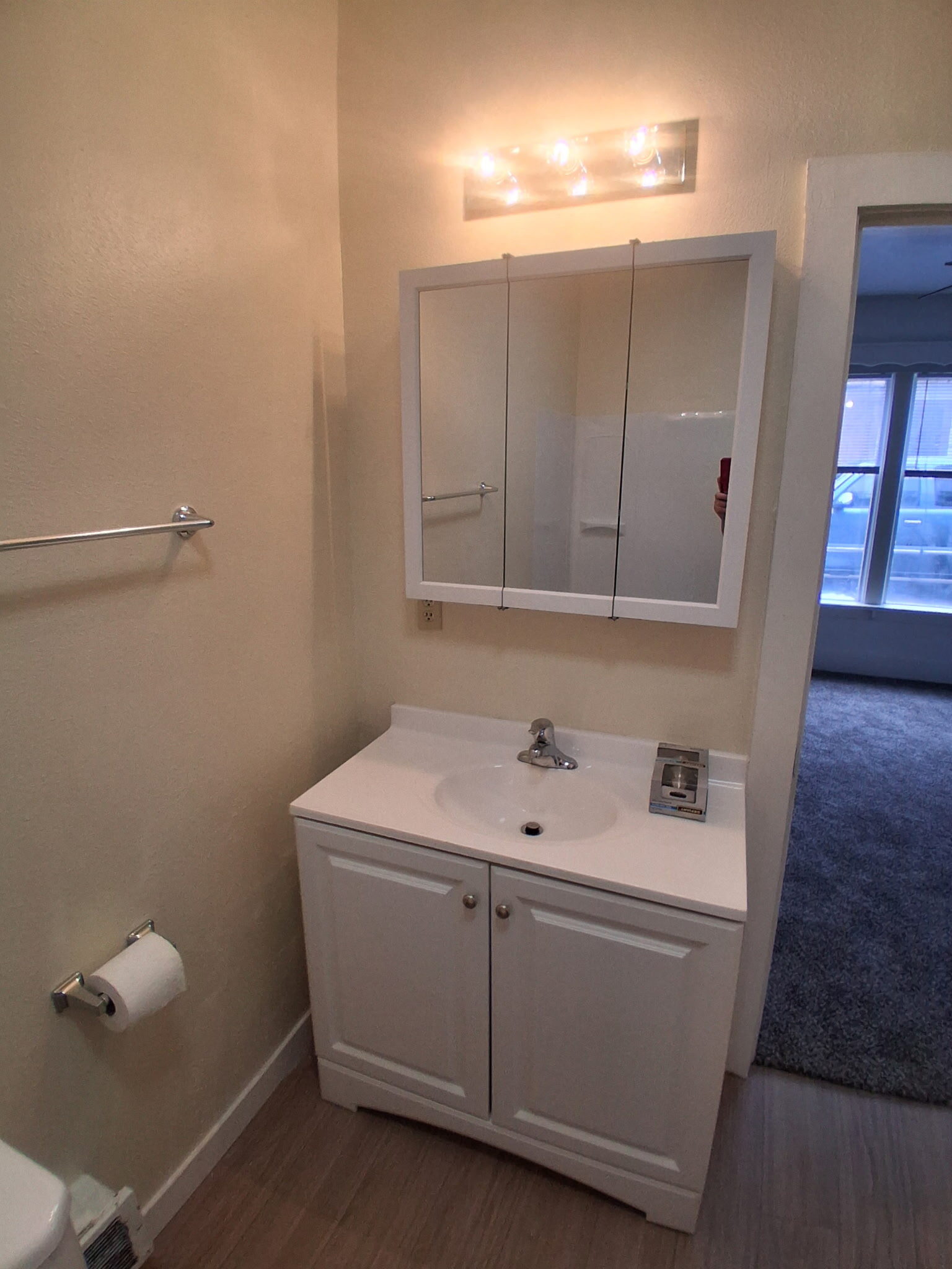 Updated bathroom vanity with white cabinet and tri-fold mirror