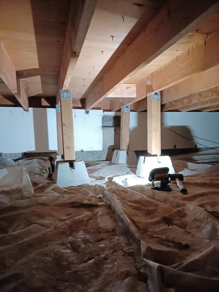 Crawl space with new wood posts on concrete piers supporting floor joists